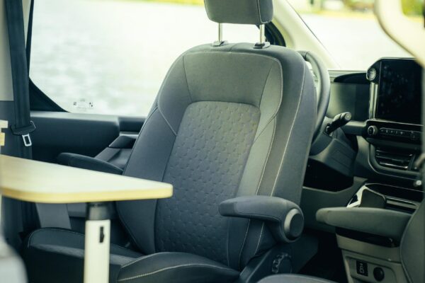 Der Fahrersitz ist um 180 Grad gedreht und zeigt mit der Sitzfläche ins Fahrzeuginnere. Vor dem Fahrersitz steht der klappbare Tisch.