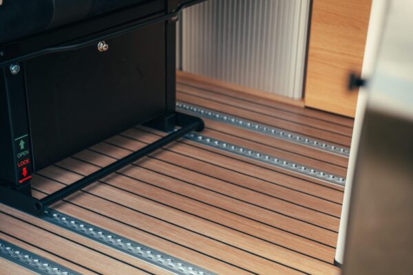 Detailaufnahme vom Smartfloor Revolution, verbaut im Ford Tourneo Custom Camper. Der Smartfloor ist im edlen Yacht-Design und es ist eine Smartbench eingesetzt. Sie lässt sich auf dem Schienensystem mühelos verschieben.