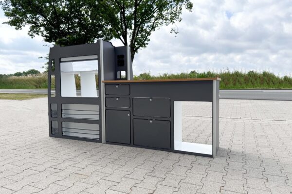 Das Smartkit Leichtbaumöbelset für den Selbstausbau des eigenen Camper Vans. Graue Fronten mit Schubladen und Schränken. Eine Arbeitsplatte in Holzoptik. Außerdem gibt es Aussparungen für den Kühlschrank und das Spülbecken.