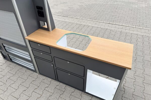 The Smartkit lightweight furniture set for converting your own camper van. Gray fronts with drawers and cupboards. A wood-look worktop. There are also cut-outs for the fridge and sink.